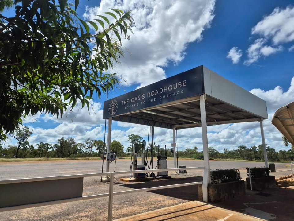 The Oasis Roadhouse sign above the fuel bowsers under a wide outback sky